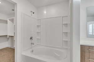 Bathroom with a spacious closet, vanity, light carpet, and shower / bathtub combination