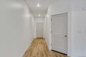 Hall featuring light wood finished floors and recessed lighting