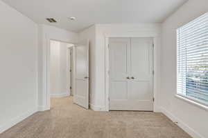 Unfurnished bedroom with light carpet and a closet