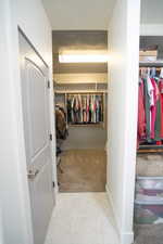 Spacious closet with light carpet and light tile patterned floors