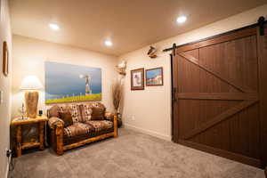 Living room with carpet flooring, a barn door, and recessed lighting