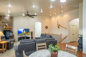 Living room featuring arched walkways, a ceiling fan, recessed lighting, a fireplace, and vaulted ceiling
