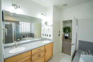 Bathroom with a garden tub, double vanity, light tile patterned floors, a stall shower, and light carpet