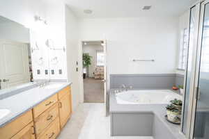 Ensuite bathroom featuring double vanity, a jetted tub, light tile patterned floors, ceiling fan, and a shower stall