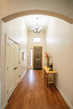 Foyer entrance featuring arched walkways, a chandelier, and dark wood-type flooring