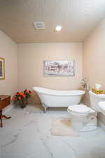 Full bath with a freestanding bath, recessed lighting, vanity, and marble look tile flooring