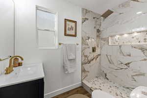 Full bath featuring a marble finish shower, vanity, wood finished floors, and a textured ceiling