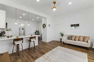 Living room with dark wood-type flooring, recessed lighting, and ceiling fan
