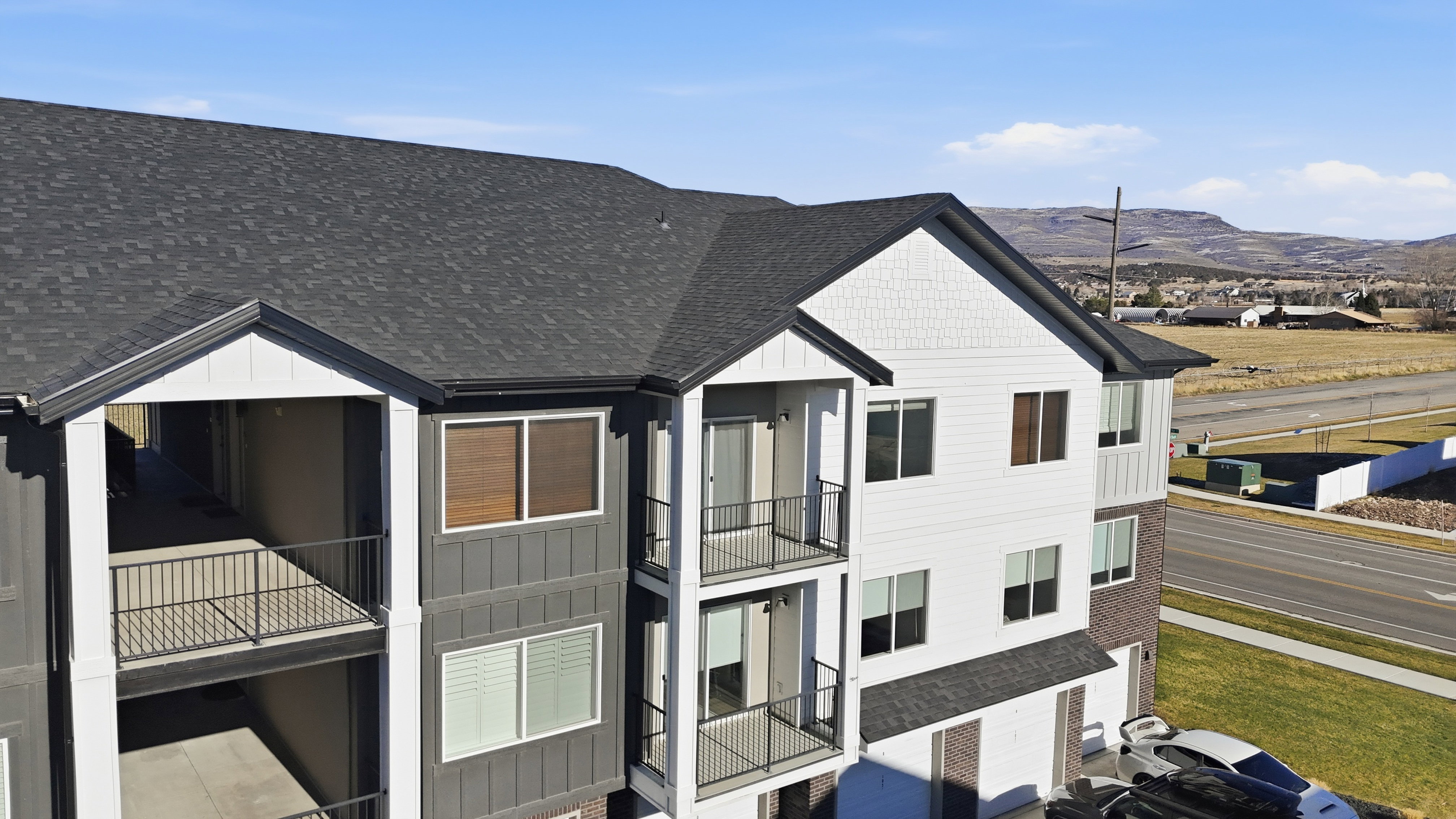 3RD FLOOR UNIT. View of front facade with a balcony, a shingled roof, a mountain view, and board and batten siding