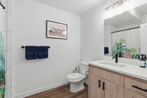 Bathroom with a shower with curtain, vanity, and dark wood finished floors