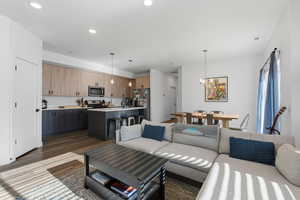 Living area featuring dark wood-style flooring, a chandelier, and recessed lighting