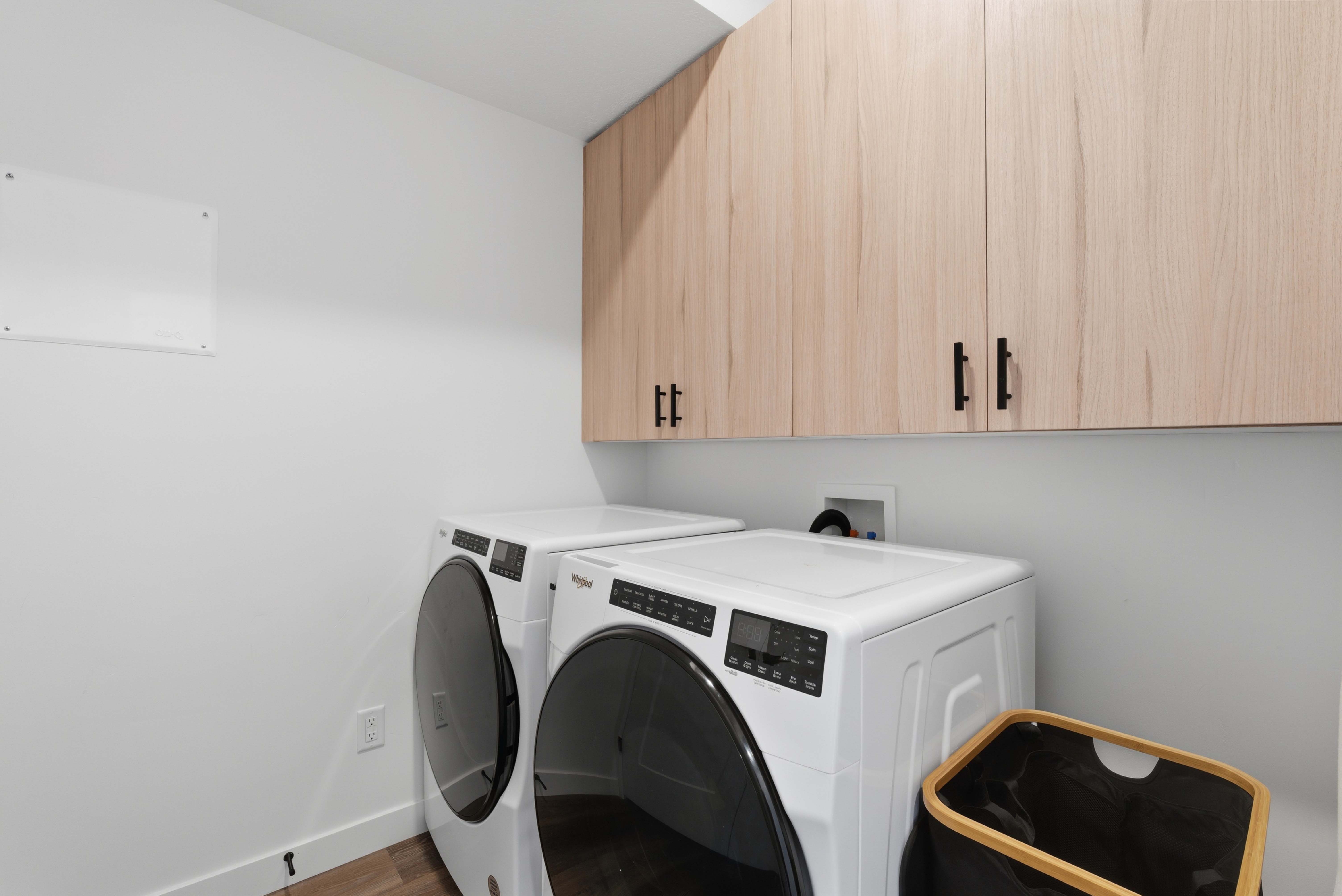 Laundry room with washer and clothes dryer, wood finished floors, and cabinet space