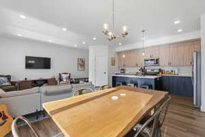 Dining room with dark wood-style flooring, recessed lighting, and a chandelier