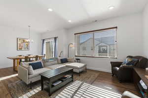 Living room with dark wood-type flooring, a chandelier, and recessed lighting