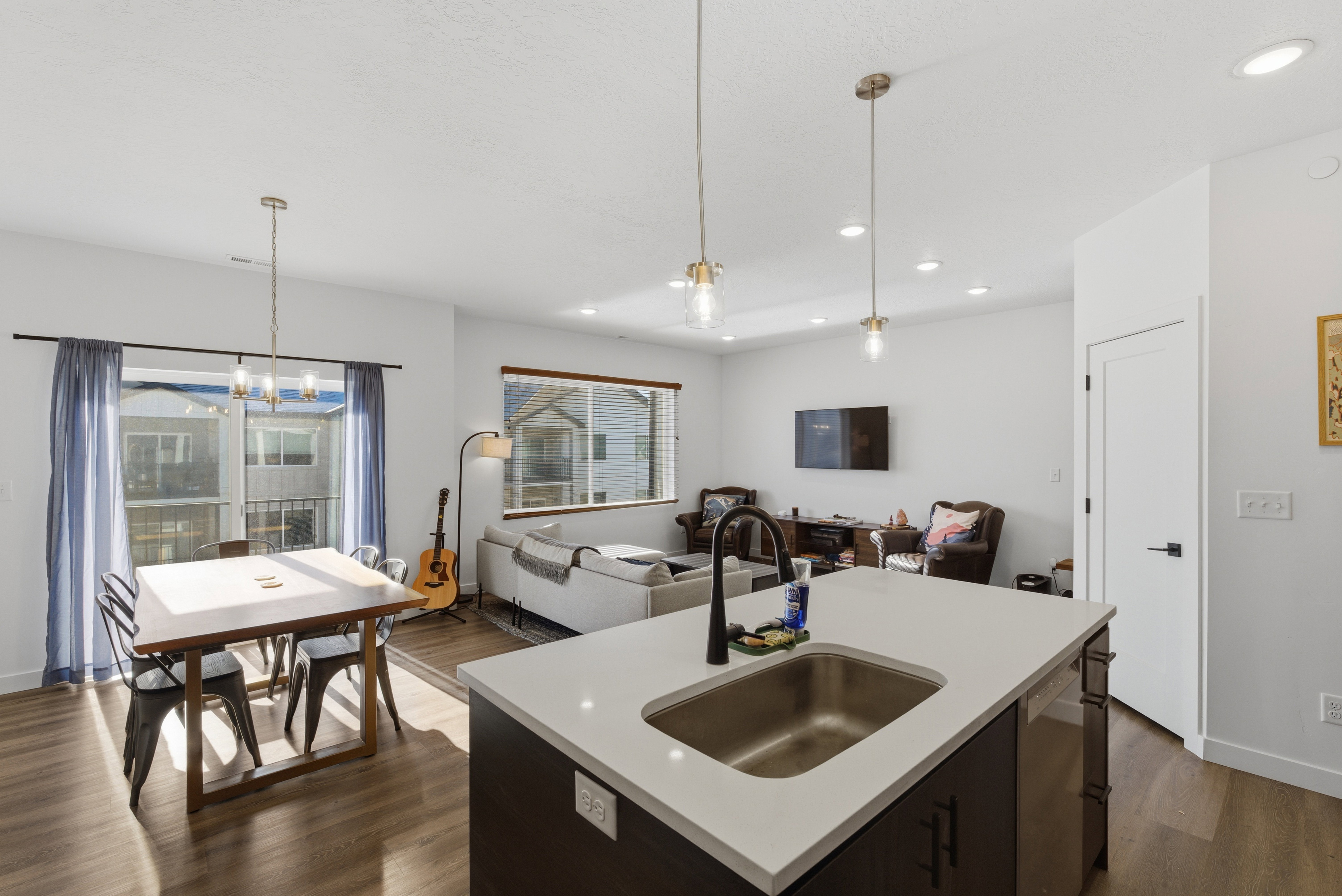 Kitchen with open floor plan, a center island with sink, decorative light fixtures, dark brown cabinets, and recessed lighting