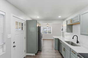 Kitchen featuring stainless steel appliances, gray cabinets, light wood-style flooring, light stone countertops, and backsplash