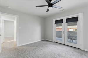 Empty room featuring light colored carpet, french doors, and a ceiling fan
