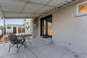 View of patio with french doors, outdoor dining space, and an outbuilding
