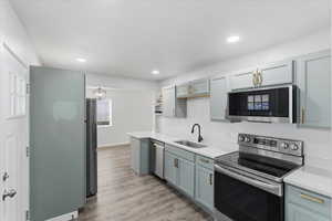 Kitchen featuring stainless steel appliances, decorative backsplash, light wood-style floors, a chandelier, and recessed lighting