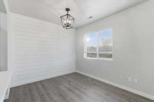 Spare room with wood finished floors, wooden walls, and a chandelier