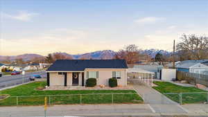 View of front facade featuring a mountain view, stucco siding, a fenced front yard, a shingled roof, and a residential view