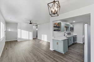 Kitchen featuring light countertops, stainless steel appliances, open shelves, a ceiling fan, and a chandelier