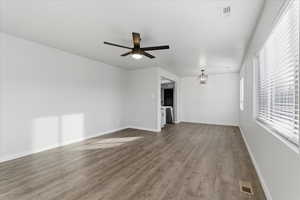 Unfurnished living room with wood finished floors, a chandelier, and a ceiling fan