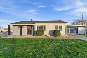 Back of property featuring a lawn, an attached carport, and driveway