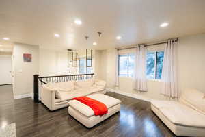 Living area with recessed lighting and dark wood-style flooring