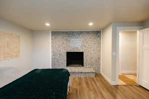 Bedroom with a high end fireplace, wood finished floors, and recessed lighting
