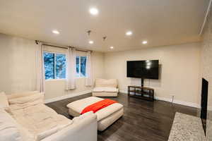 Living area featuring recessed lighting, dark wood finished floors, and a large fireplace