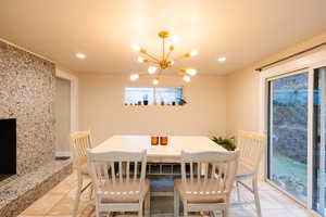 Dining space with a chandelier, light tile patterned floors, recessed lighting, and a high end fireplace