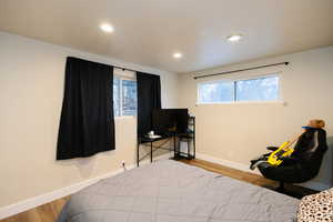 Bedroom featuring wood finished floors, multiple windows, and recessed lighting