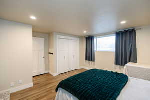 Bedroom with light wood finished floors, a closet, and recessed lighting