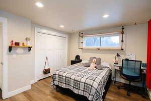 Bedroom with wood finished floors, a closet, recessed lighting, and an office area
