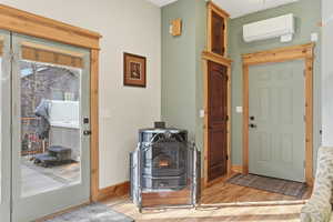 Entrance foyer featuring an AC wall unit, wood finished floors, and a wood stove