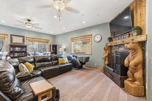 Carpeted living room with a fireplace, healthy amount of natural light, recessed lighting, and a ceiling fan
