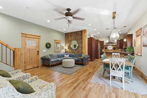 Living area featuring stairway, light wood-style flooring, a ceiling fan, and recessed lighting