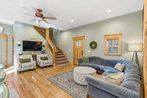 Living area with stairs, wood finished floors, ceiling fan, healthy amount of natural light, and recessed lighting