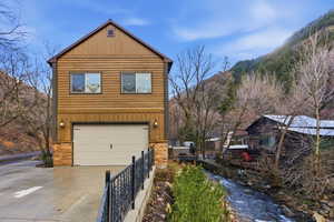 View of property exterior with driveway, stone siding, and an attached garage