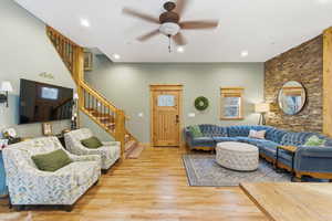 Living area featuring stairway, wood finished floors, a ceiling fan, and recessed lighting