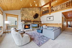Living area with wooden ceiling, a stone fireplace, carpet flooring, high vaulted ceiling, and recessed lighting