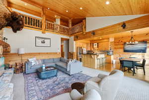 Living area with wooden walls, wooden ceiling, a wainscoted wall, recessed lighting, and a chandelier