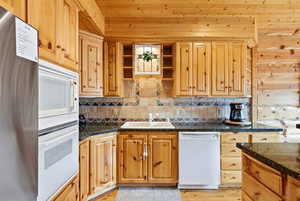 Kitchen with white appliances, backsplash, open shelves, and light wood-style flooring