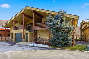 View of front of house with stone siding, a garage, a balcony, and driveway