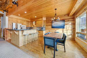 Dining room with wooden walls, wooden ceiling, a chandelier, light wood finished floors, and recessed lighting