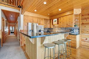 Kitchen featuring open shelves, wood ceiling, a kitchen breakfast bar, a kitchen island, and appliances with stainless steel finishes