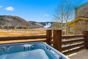 Snow covered pool featuring a hot tub and a mountain view
