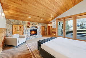 Bedroom featuring wooden ceiling, carpet flooring, a stone fireplace, vaulted ceiling, and access to exterior