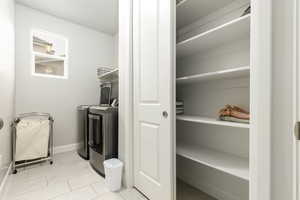 Laundry room with separate washer and dryer and light tile patterned floors
